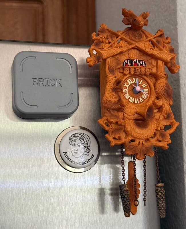 Cuckoo clock fridge magnet with detailed carvings beside a square magnet labeled