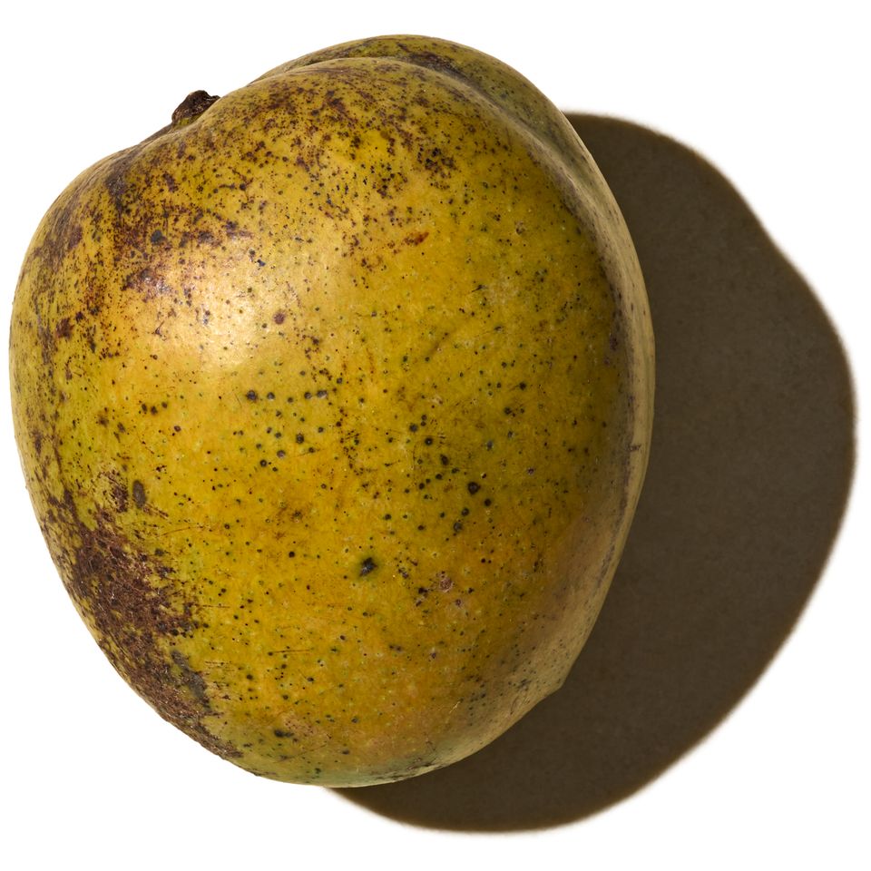 A mango with visible texture and shadow