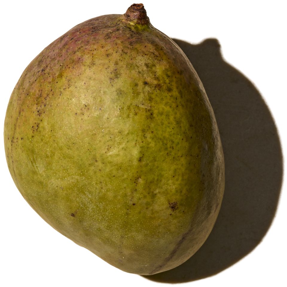 A mango set against a white background casting a shadow