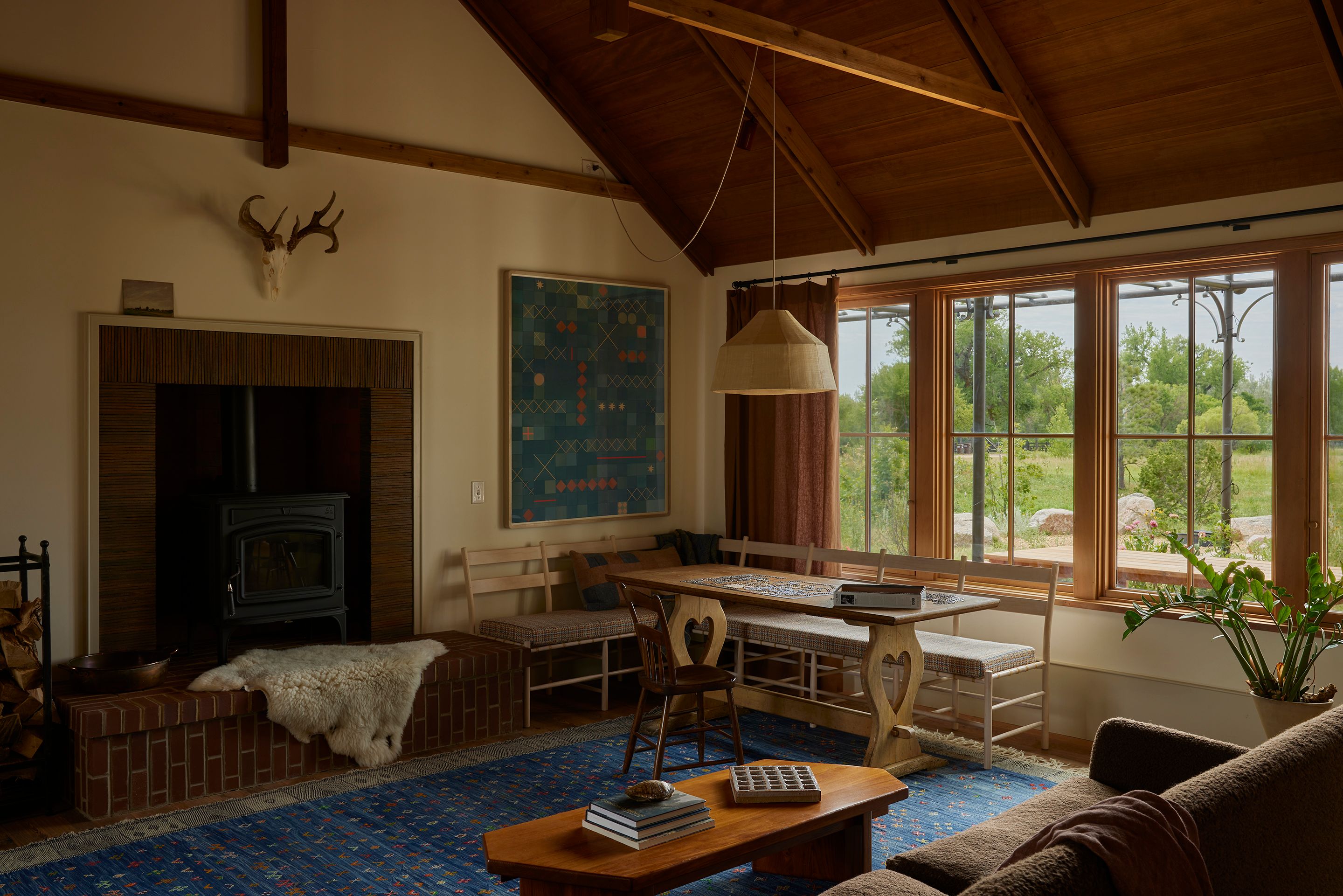 A large fireplace is the focal point of the living room. A Carrabassett front-loading wood stove by Jotul is surrounded by dreadnought creasing tiles, and to the right is an untitled collage by Lena Wolff (from Sarah Shepard Gallery) hanging above a customized Windham sofa in bleached maple by Brian Persico. To the left of the fireplace is a custom log holder designed by Landed Interiors in collaboration with Shawn Lovell Metalworks, who uses traditional mortise and tenon joinery. “I think this speaks to both our clients’ precision of taste—nothing we were finding that was premade felt quite right, and everything we all liked in photographs appeared to be custom—and support of artisans and the trades,” says Menegat. “Like much of the house, the design is fairly simple but thoughtfully considered and really sings in the details when you slow down enough to look closely.”