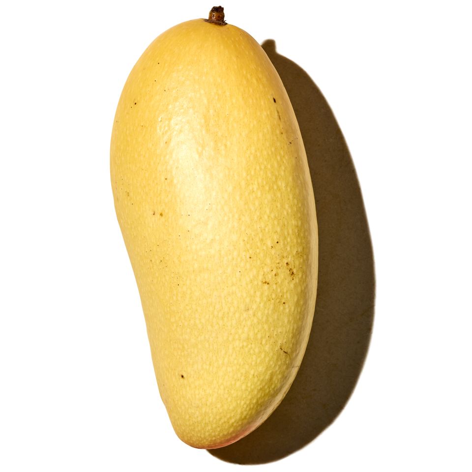 A golden elephant mango displayed against a white background