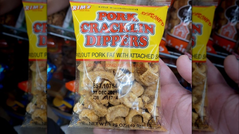 A hand holds a bag of Brim's Pork Cracklin Dippers