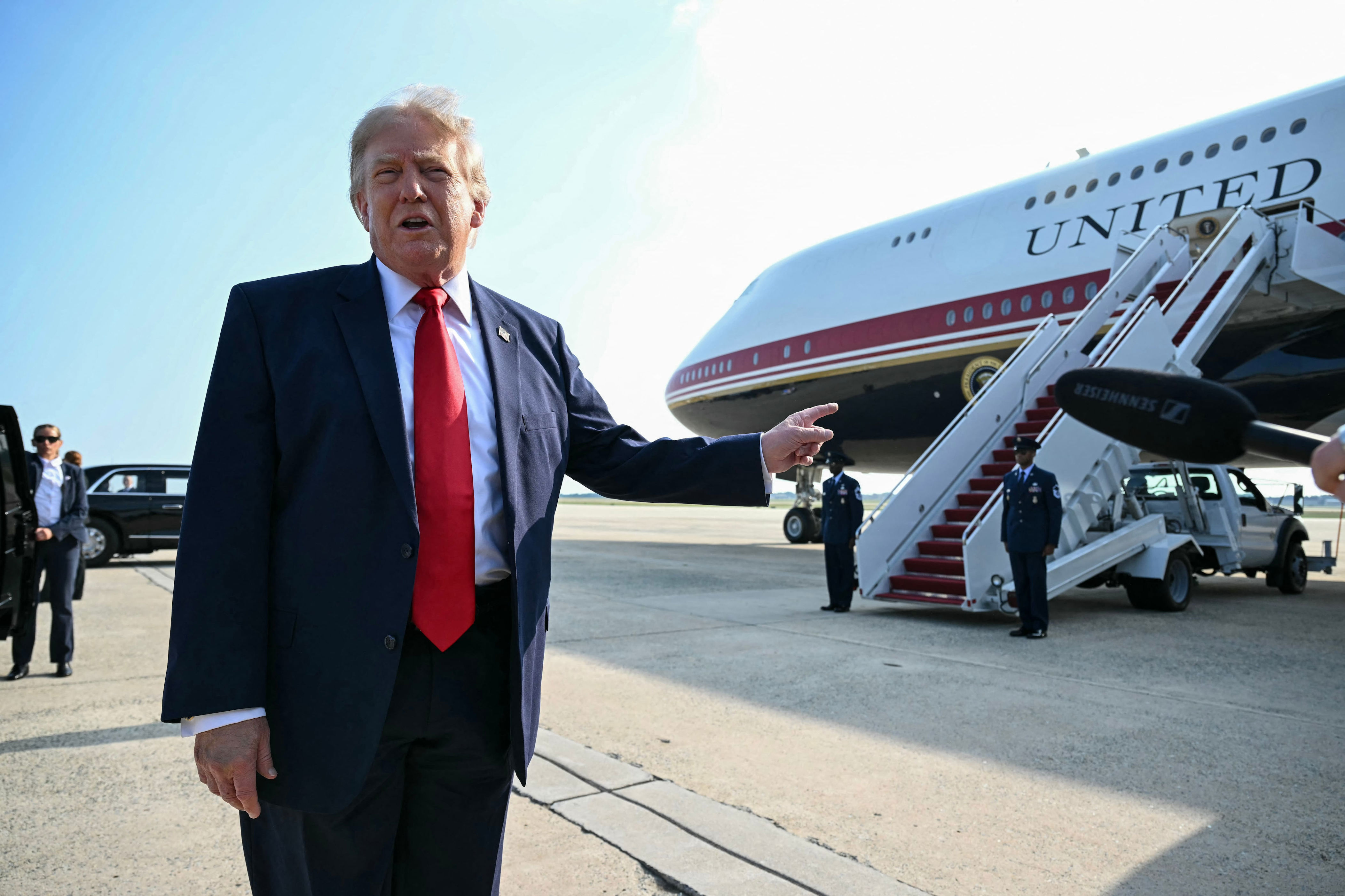 US President Donald Trump points to his free gift. / SAUL LOEB / AFP via Getty Images