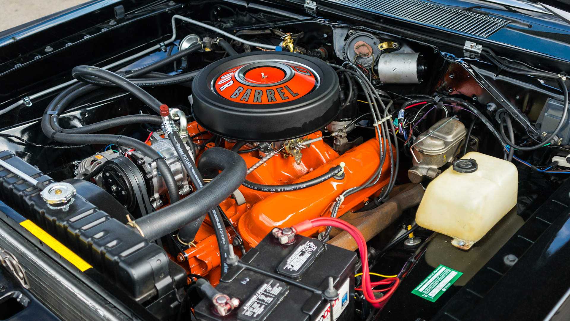 Orange V8 engine under a black Dodge Dart muscle car hood