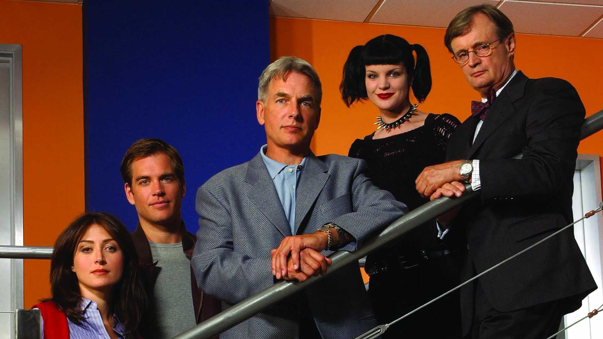 The early cast of NCIS, including Mark Harmon and Michael Weatherly, standing together in a promotional photo