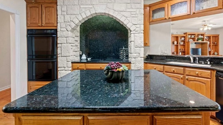 Tuscan style kitchen with stone alcove, Blue Pearl granite counters, and maple wood cabinets