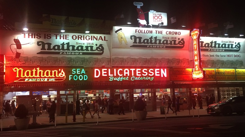 Exterior of Nathan's Famous at night with neon signs lit