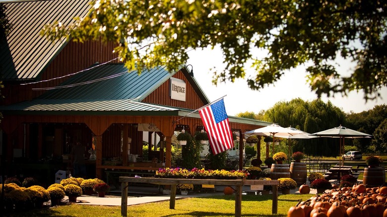 American flag hanging outside of William Heritage Winery, with patio tables, flowers, and pumpkins in a fall setting.