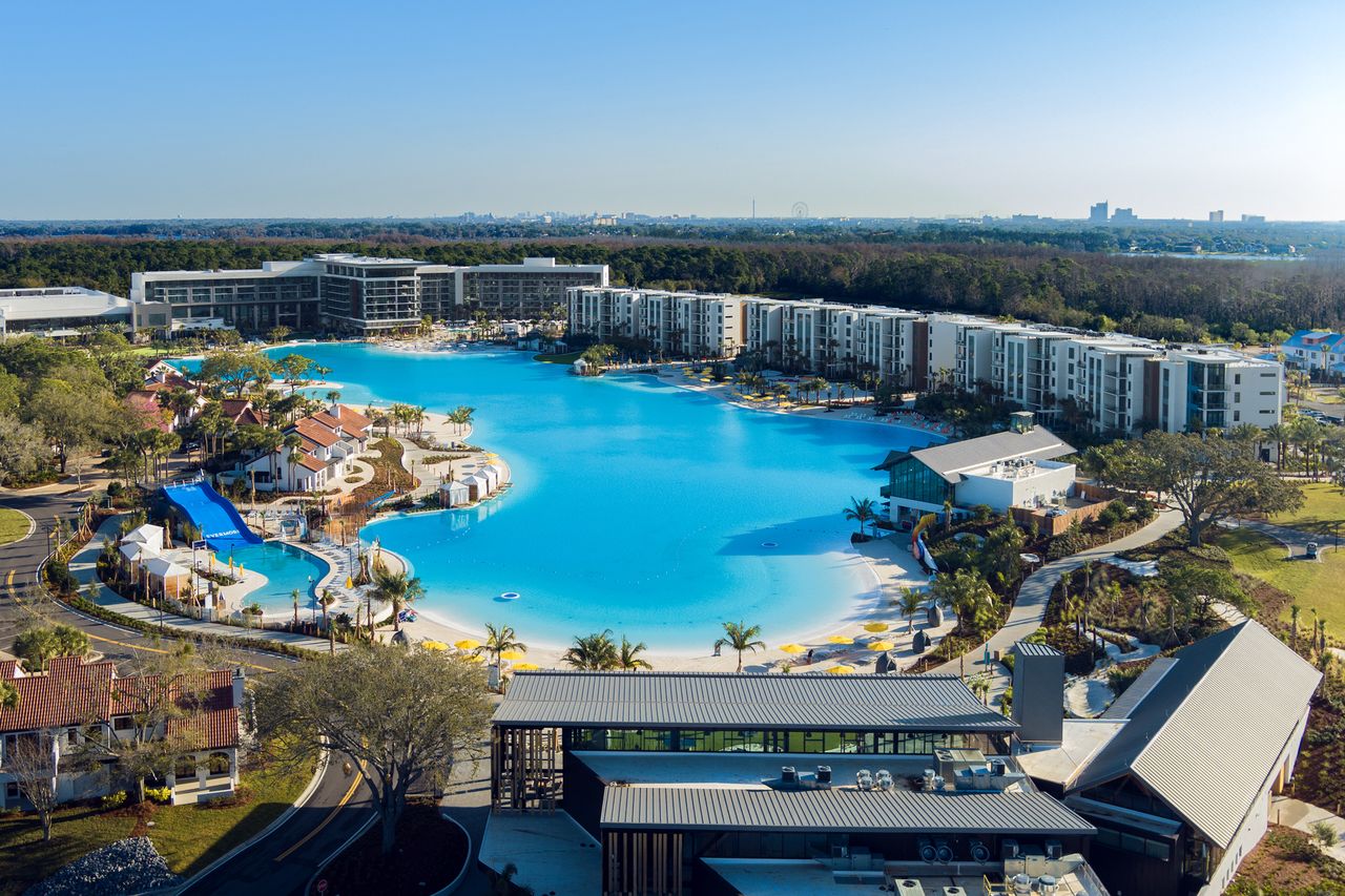 Aerial view of a resort with a large lagoonstyle pool and surrounding buildings