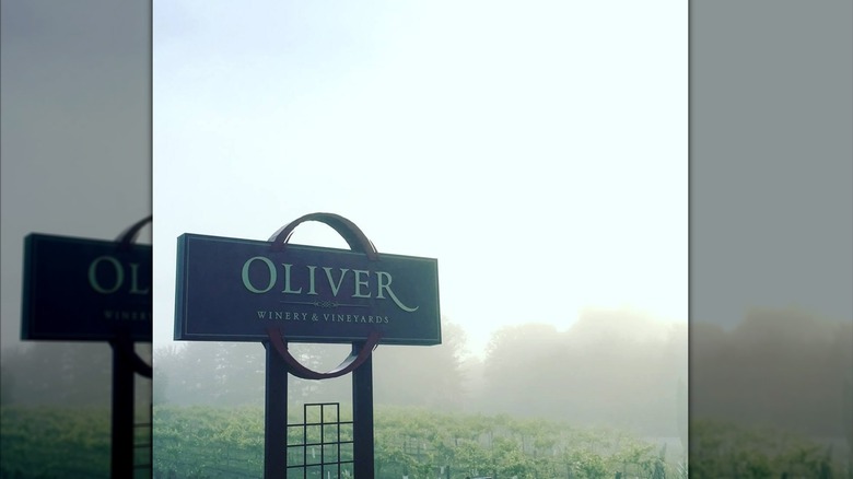 Oliver Winery sign overlooking vineyards on a hazy day.