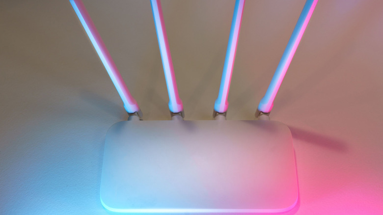 White router on table with pink and blue lights shining on it