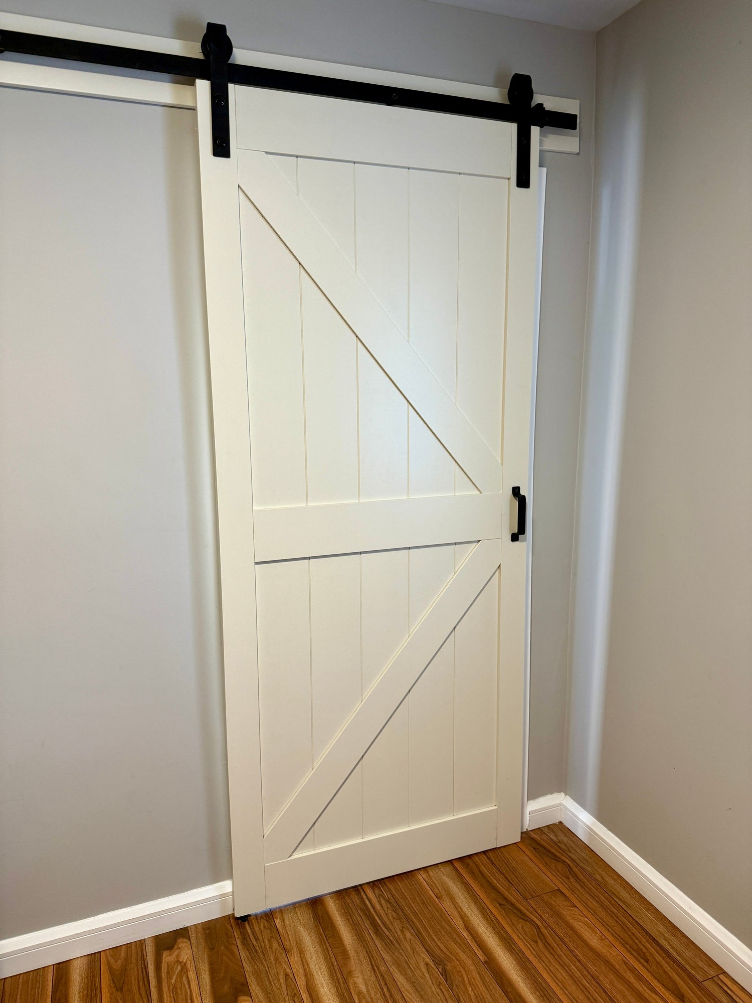 Wooden barn door on a sliding track in a modern room with hardwood floors