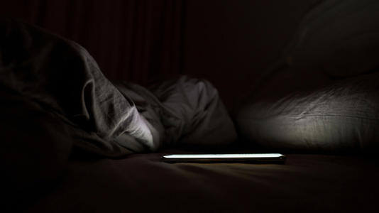 A phone placed on a bed in a dark room