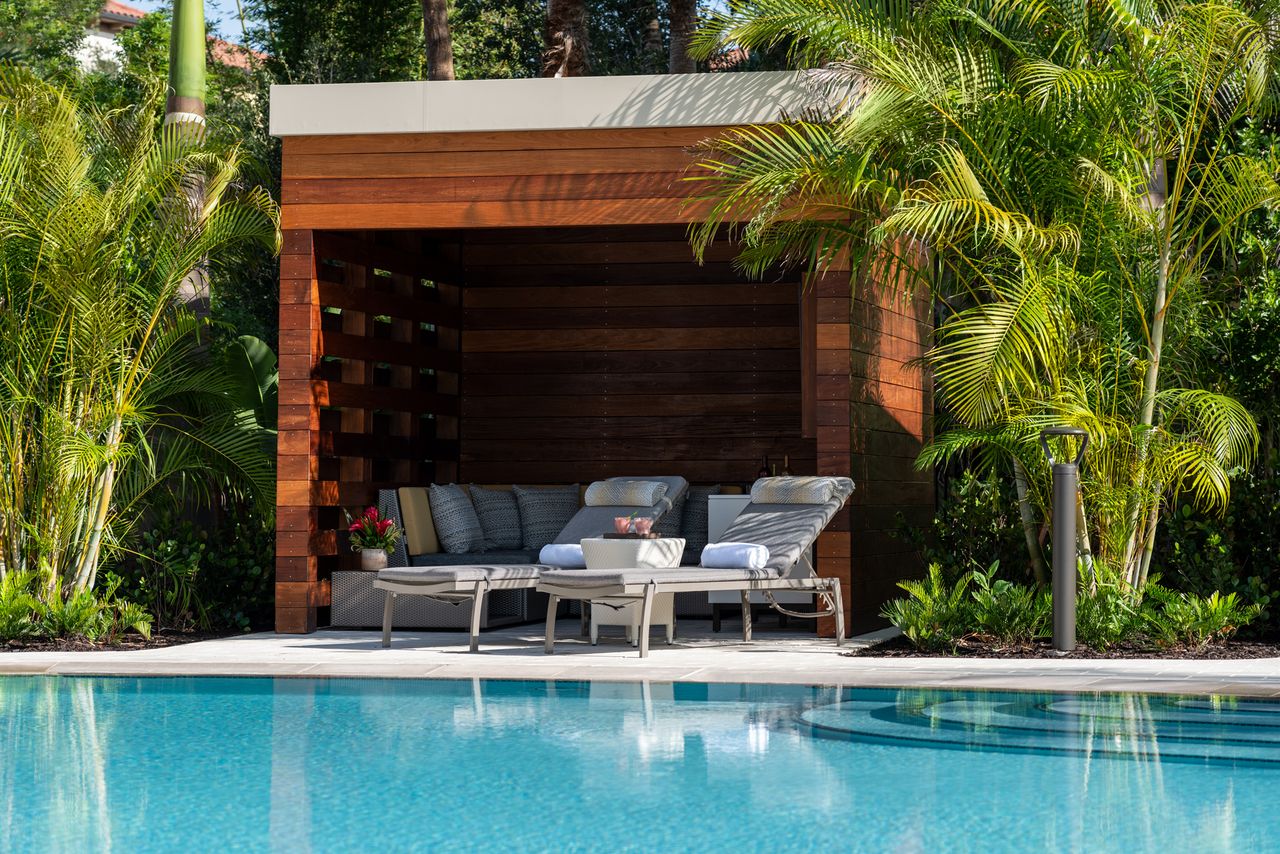 Poolside cabana with lounge chairs surrounded by tropical plants
