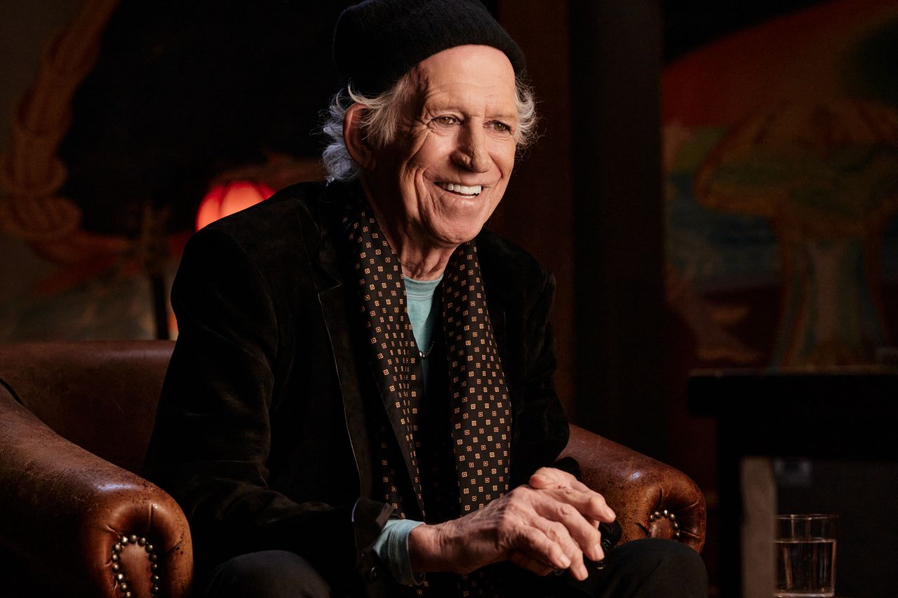 Keith Richards seated smiling in an indoor setting