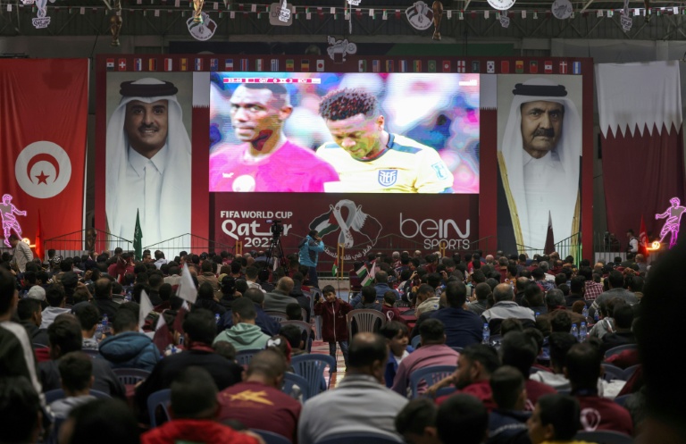 مشجعون فلسطينيون يشاهدون بثا مباشرا للمباراة الافتتاحية لكأس العالم 2022 بين قطر والإكوادور عبر شاشة عملاقة نُصبت بين صورتين لأمير قطر الشيخ تميم بن حمد آل ثاني ووالده الأمير السابق الشيخ حمد بن خليفة آل ثاني داخل صالة رياضية مغطاة في مدينة غزة في 20 تشرين الثاني/نوفمبر 2022