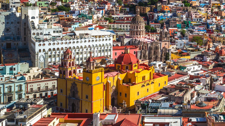 Aerial view of Guanajuato, Mexico, with a bright yellow cathedral and other Baroque buildings at the center