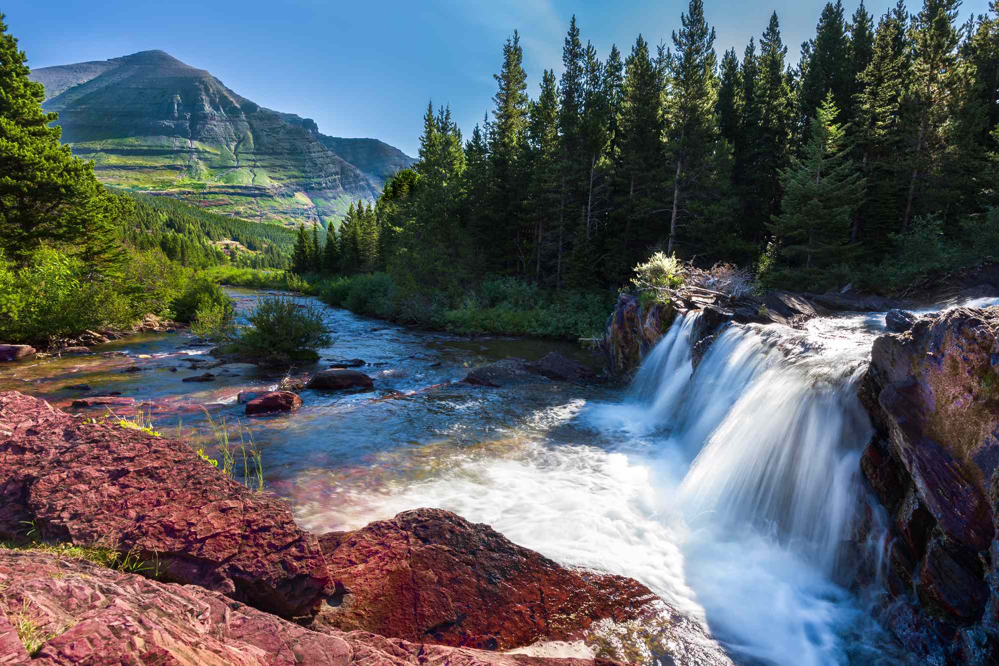Waterfall and river in a forested mountainous landscape