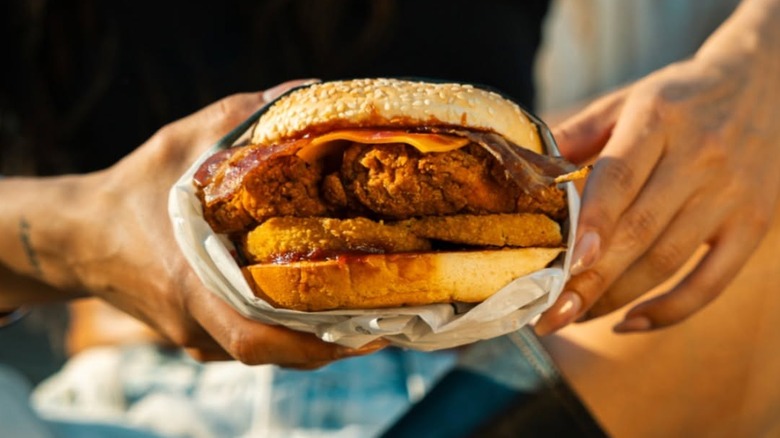 A person holding a Western Bacon Chicken Sandwich from Carl's Jr.