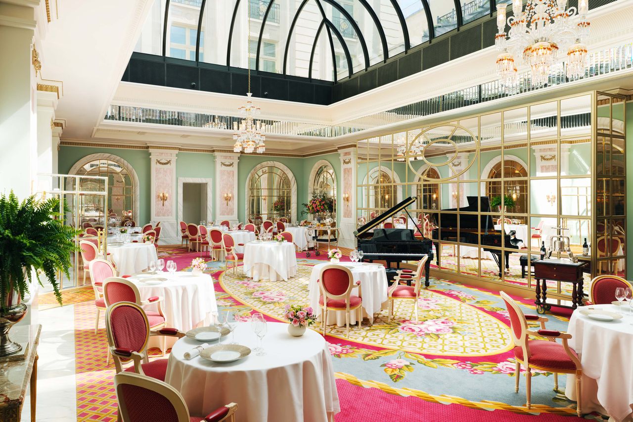 Elegant dining room in a luxury hotel with tables chairs a grand piano and arched windows featuring a glass ceiling