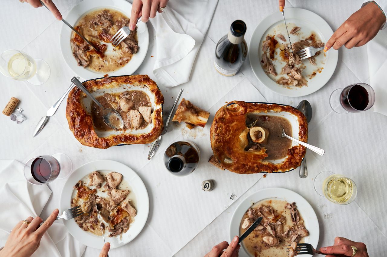 A table with plates of food shared dishes and wine glasses