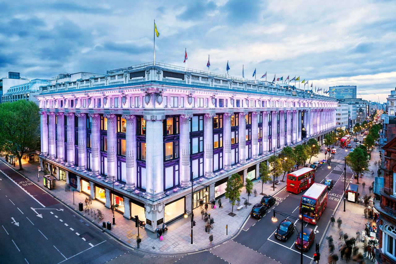 Selfridges department store on Oxford Street London seen with a busy street and traffic including a red doubledecker bus