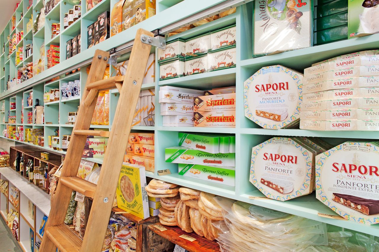 Shelved deli products with a wooden ladder in an Italian specialty store