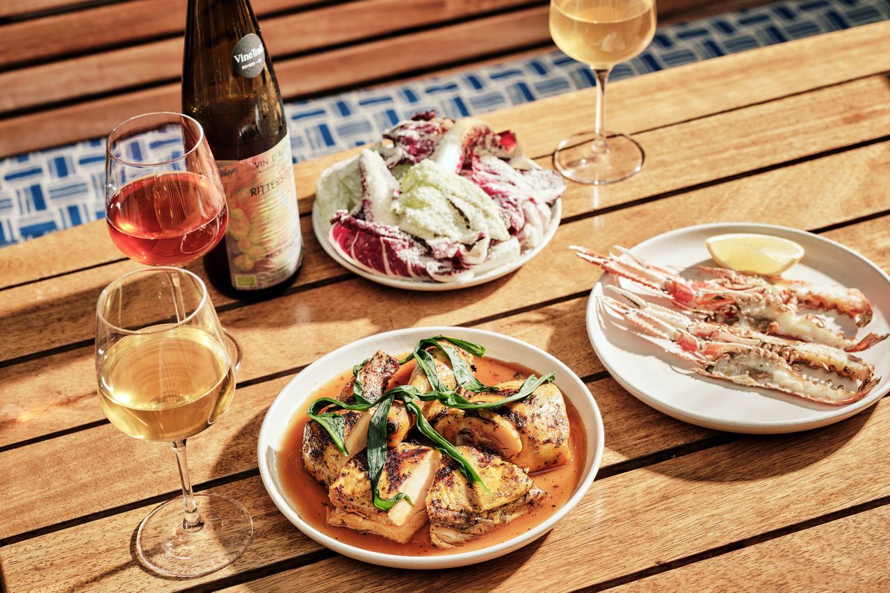 A table at Isla with dishes of food beverages and tableware arranged outdoors