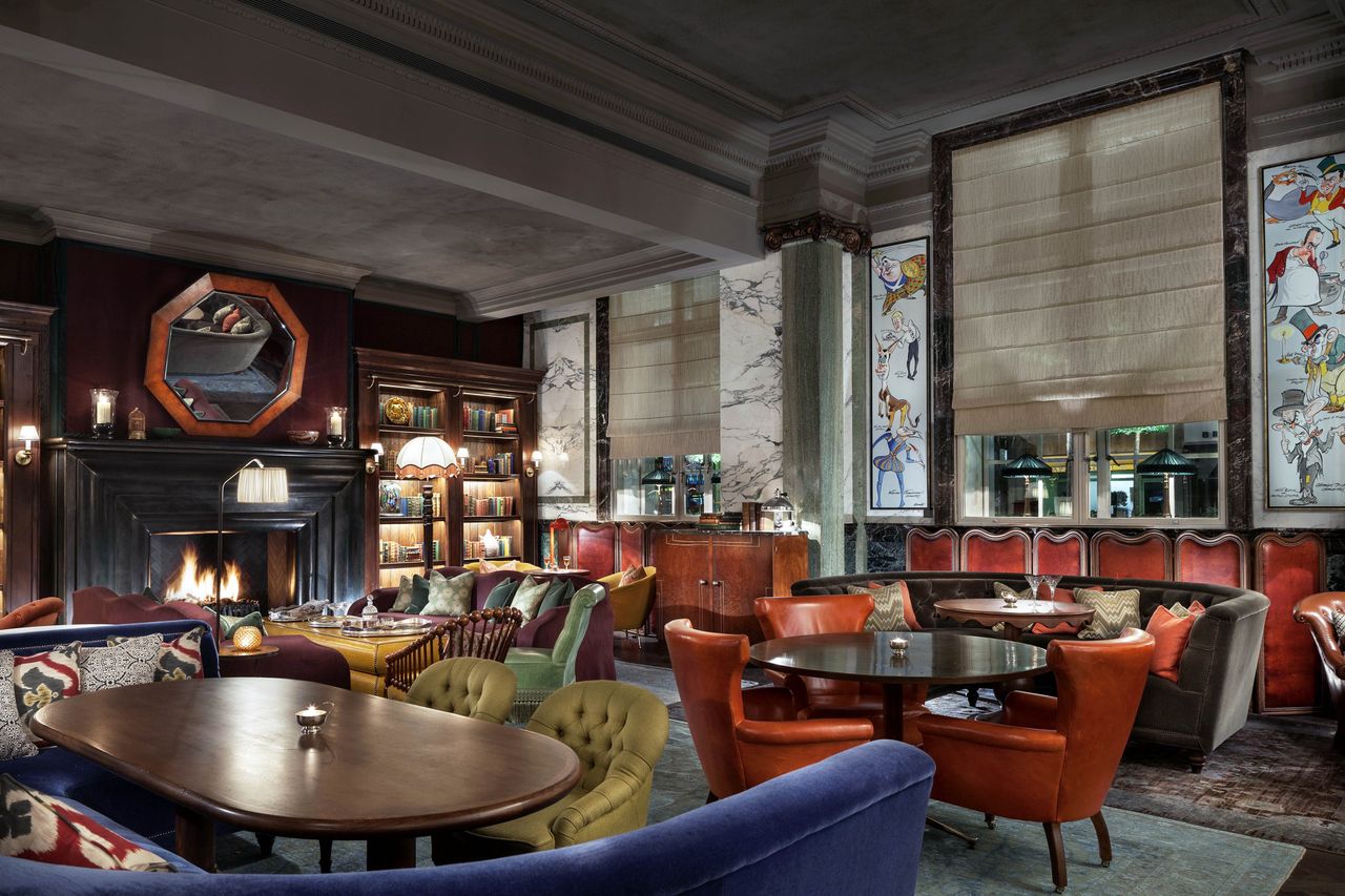 A luxurious room with comfortable seating and tables featuring a fireplace and decorative art on the walls