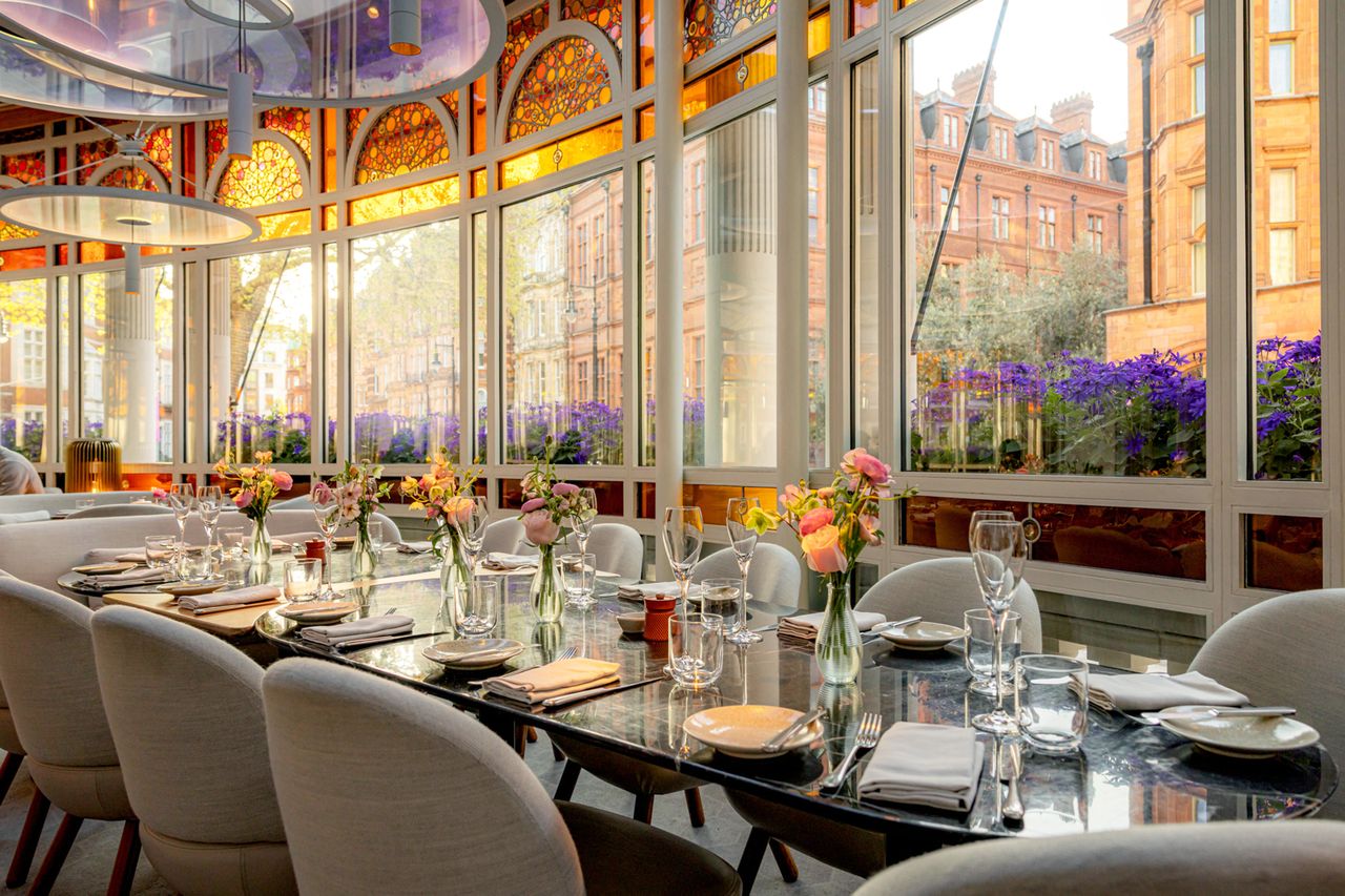 Dining table set in an elegant restaurant with large windows and floral decor
