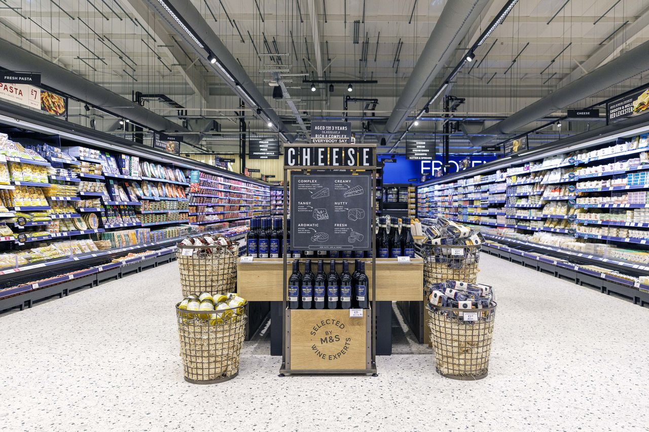 Grocery store interior with a cheese display in the center shelves stocked with products on both sides