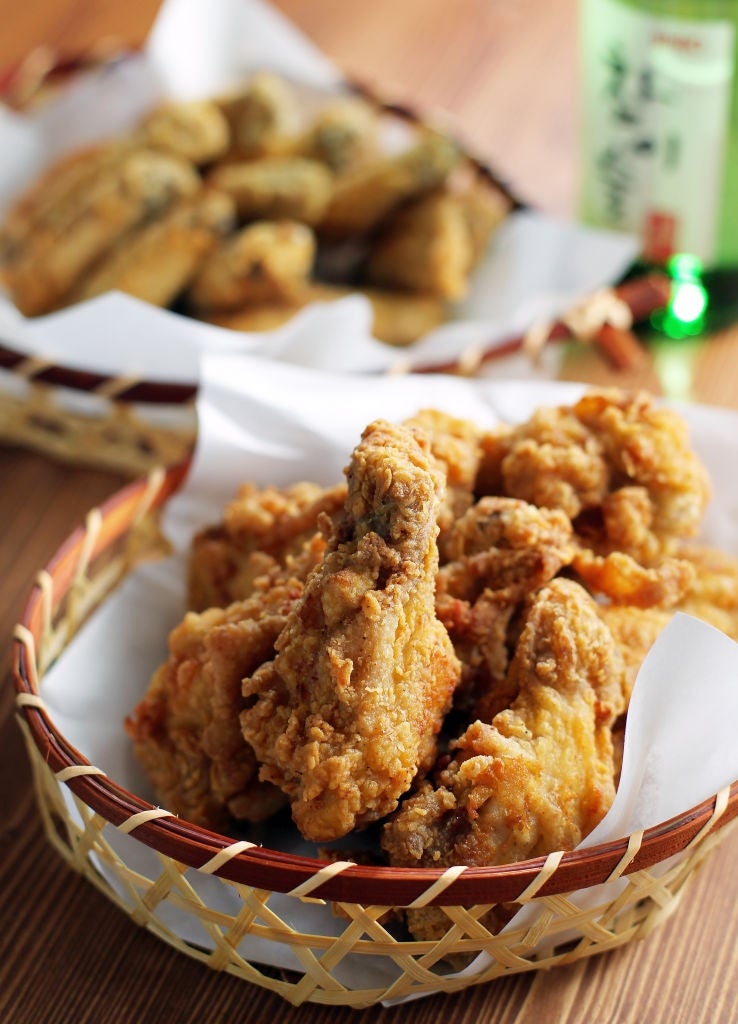 Basket of crispy fried chicken with dipping sauce and another basket of fried vegetables in the background