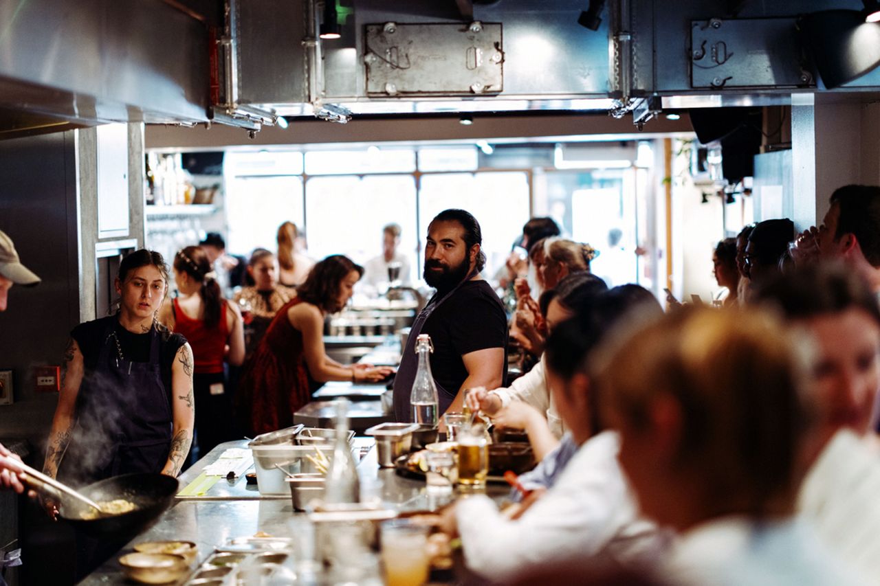 Crowded restaurant interior with people dining and staff working