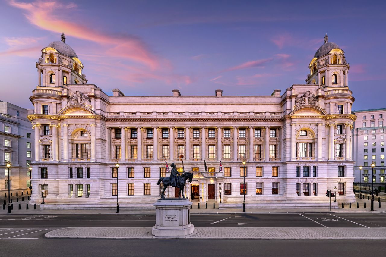 Front view of a classicalstyle building with a prominent statue of a horse and rider in front symmetrical architecture and twilight backdrop