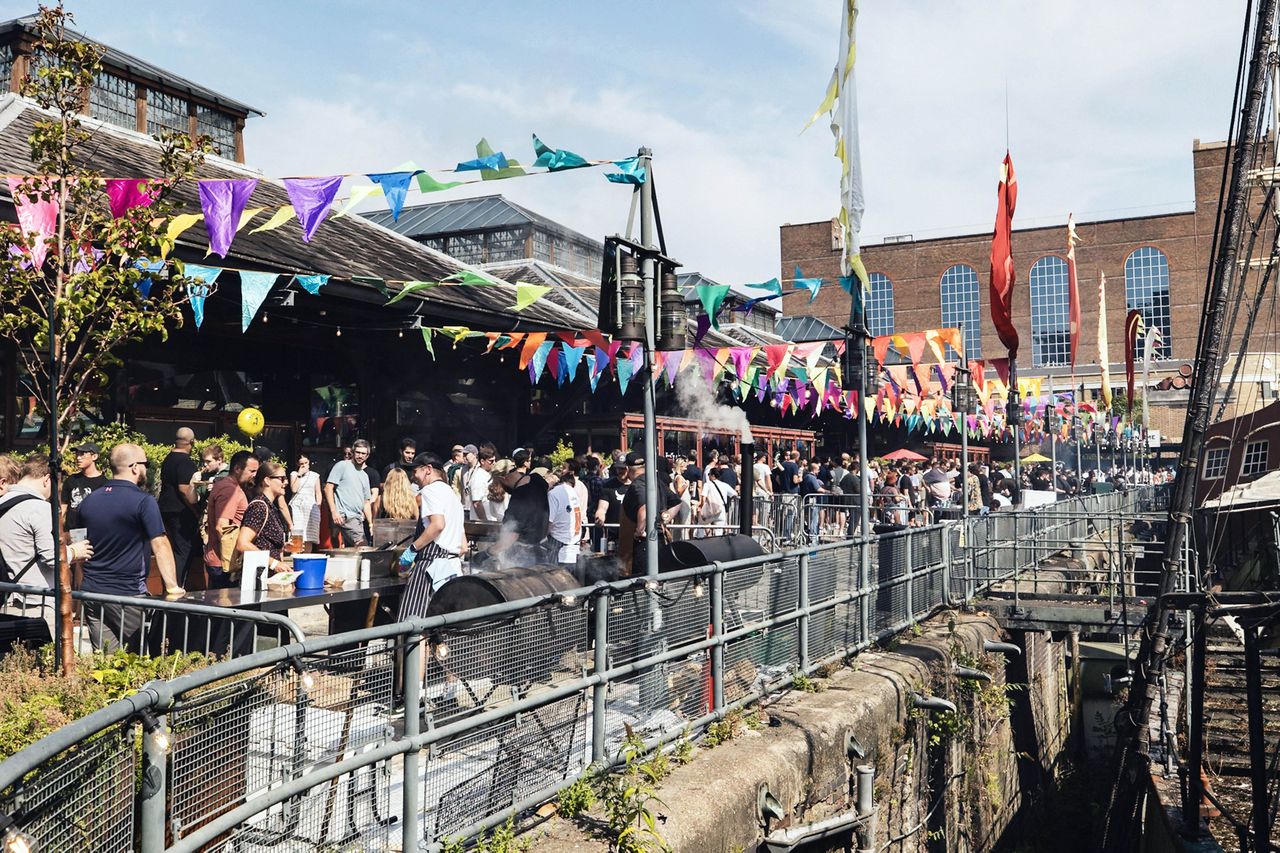Outdoor festival with people attending colorful bunting decorating the area industrialstyle setting