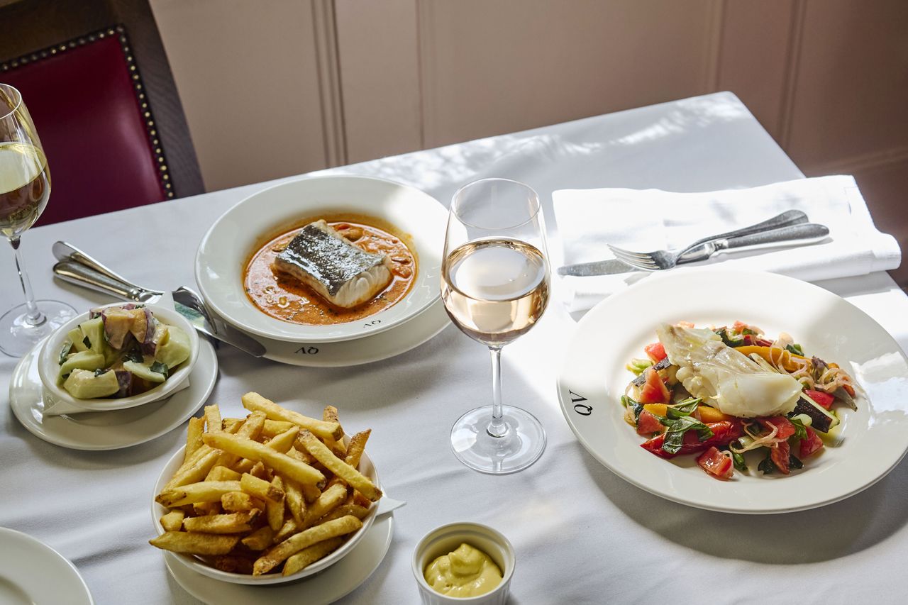 A table set with various plates of food including fish fries and wine