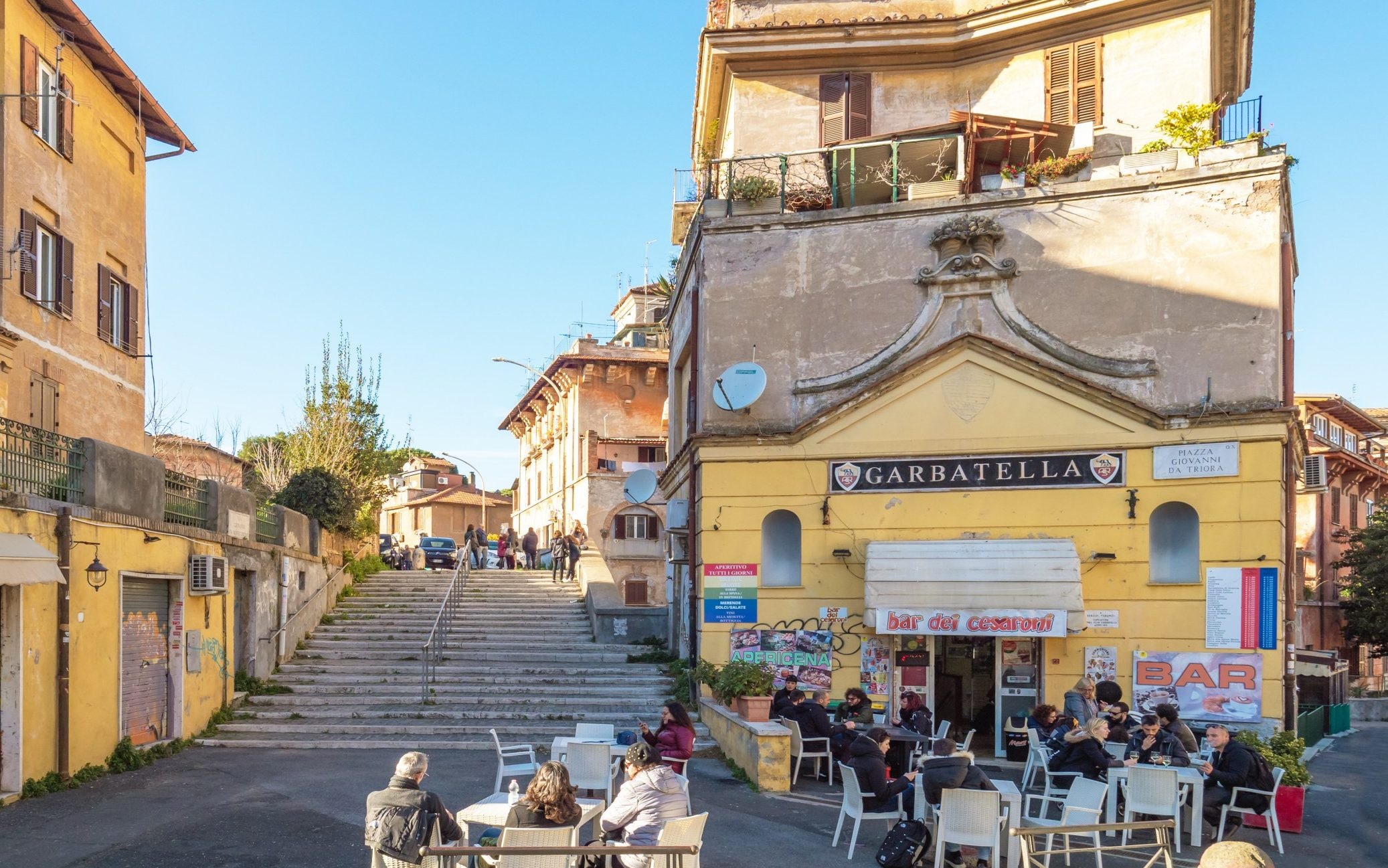 Yellow buildings and people sat on tables outside cafe