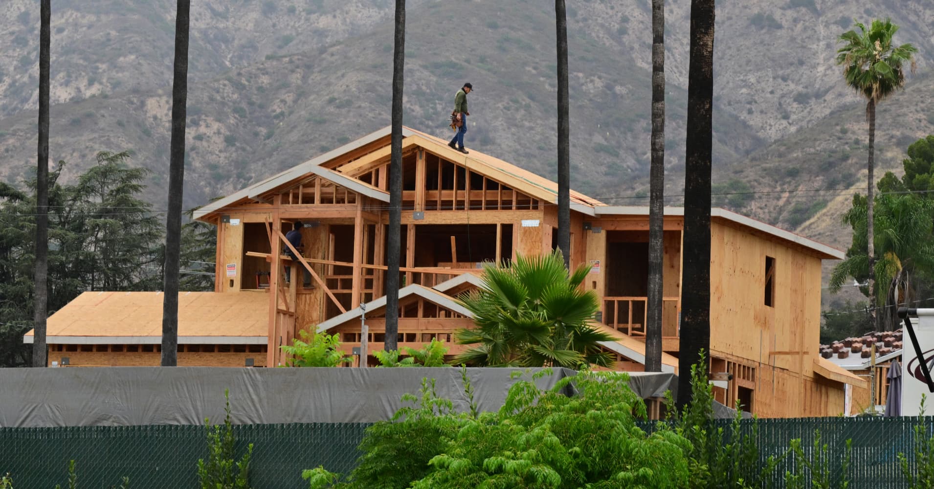 Contractors work on building a new house as survivors of the 2025 Eaton Fire hold a demonstration in Altadena, California, on June 29, 2026.