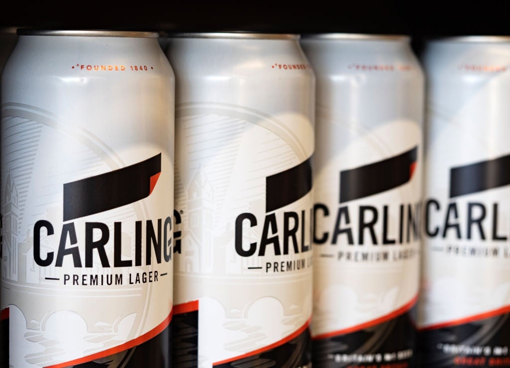 Cans of Carling Premium Lager are displayed in a row on a shelf