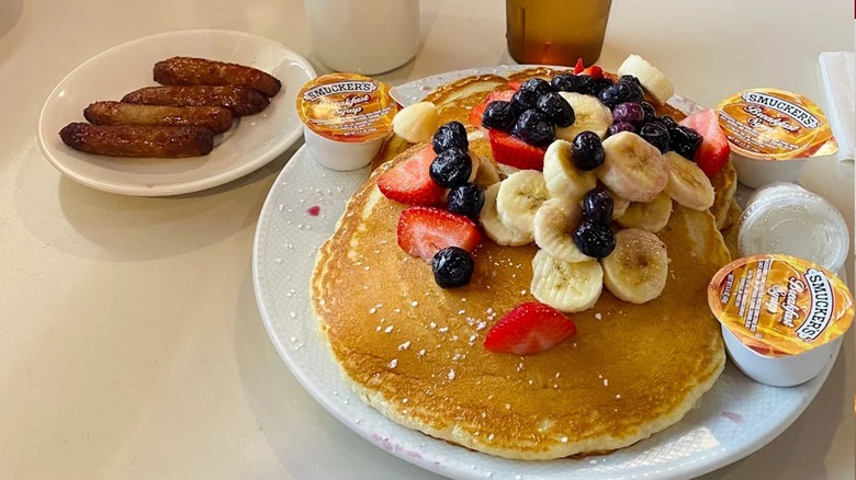 Pancakes topped with fruit and a side of sausages at Four Seasons Diner
