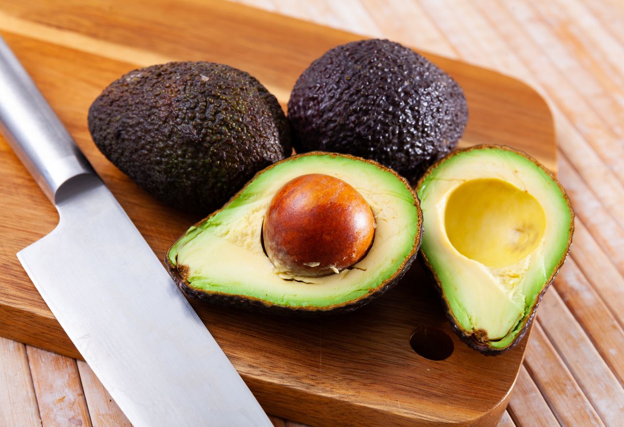 Fresh avocados cut in half on wooden cutting board