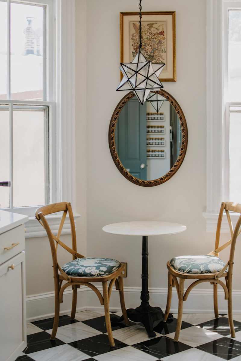 Vintage mirror above bistro table in kitchen.