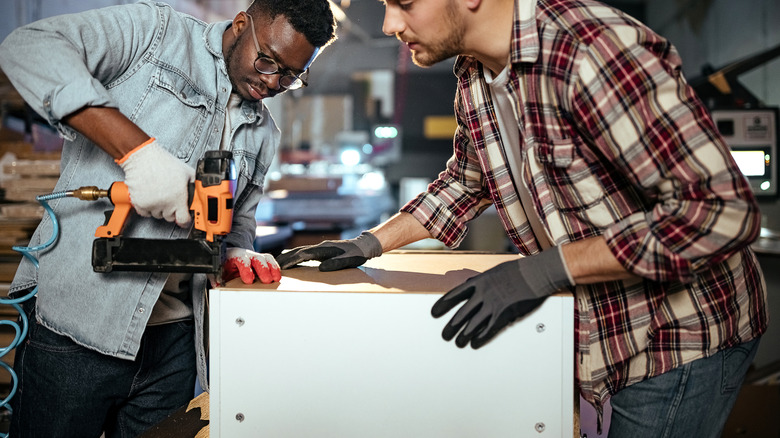 two people building something with brad nailer