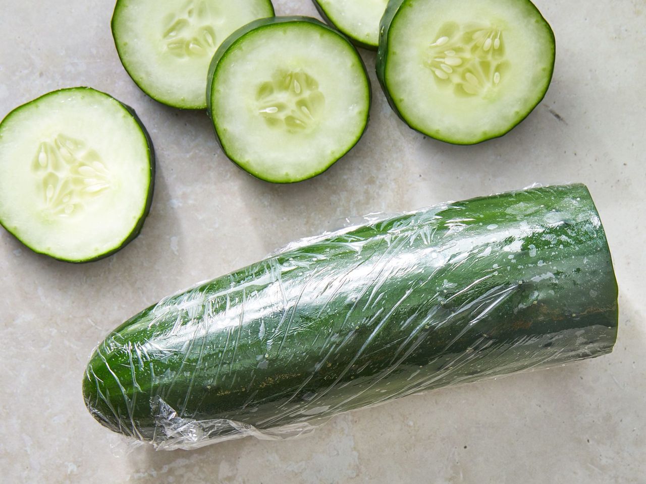 a wrapped cucumber beside cucumber slices