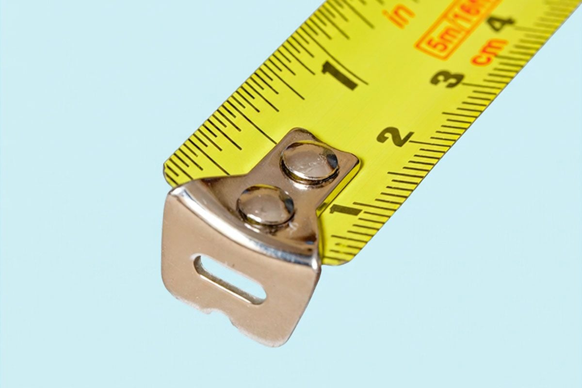 The end of a yellow tape measure marked in inches and cm.