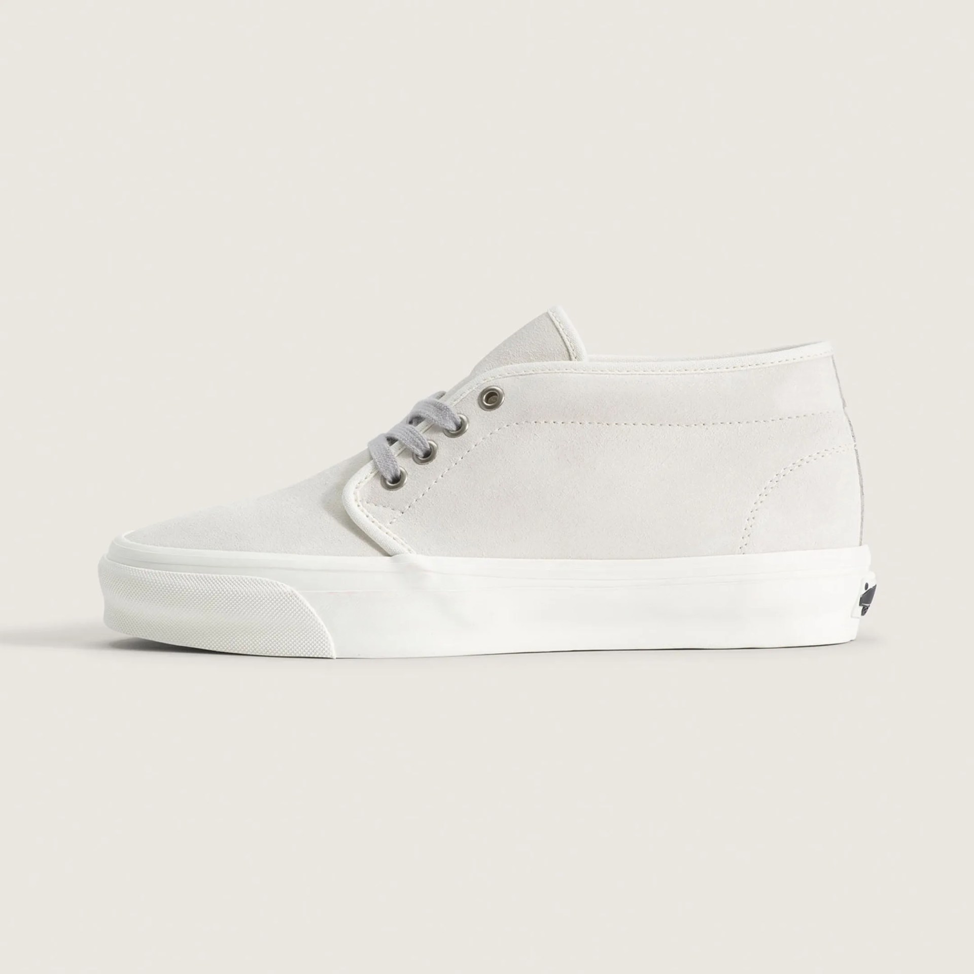 Off-white suede high-top sneaker with gray laces and white rubber sole on a beige background.
