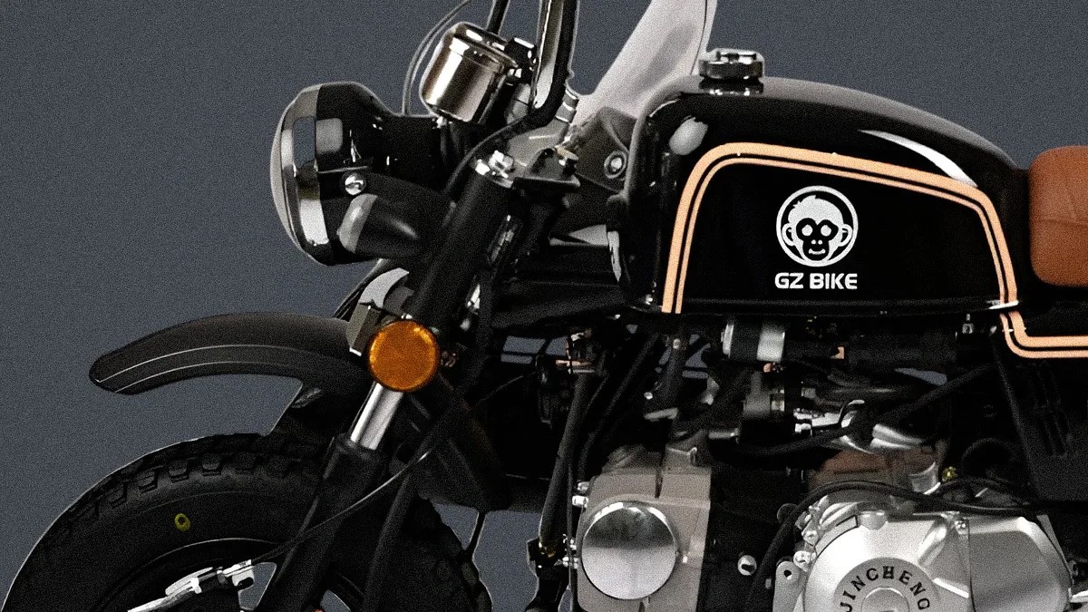 Close-up of a black GZ Bike motorcycle fuel tank with a monkey logo and tan seat visible.
