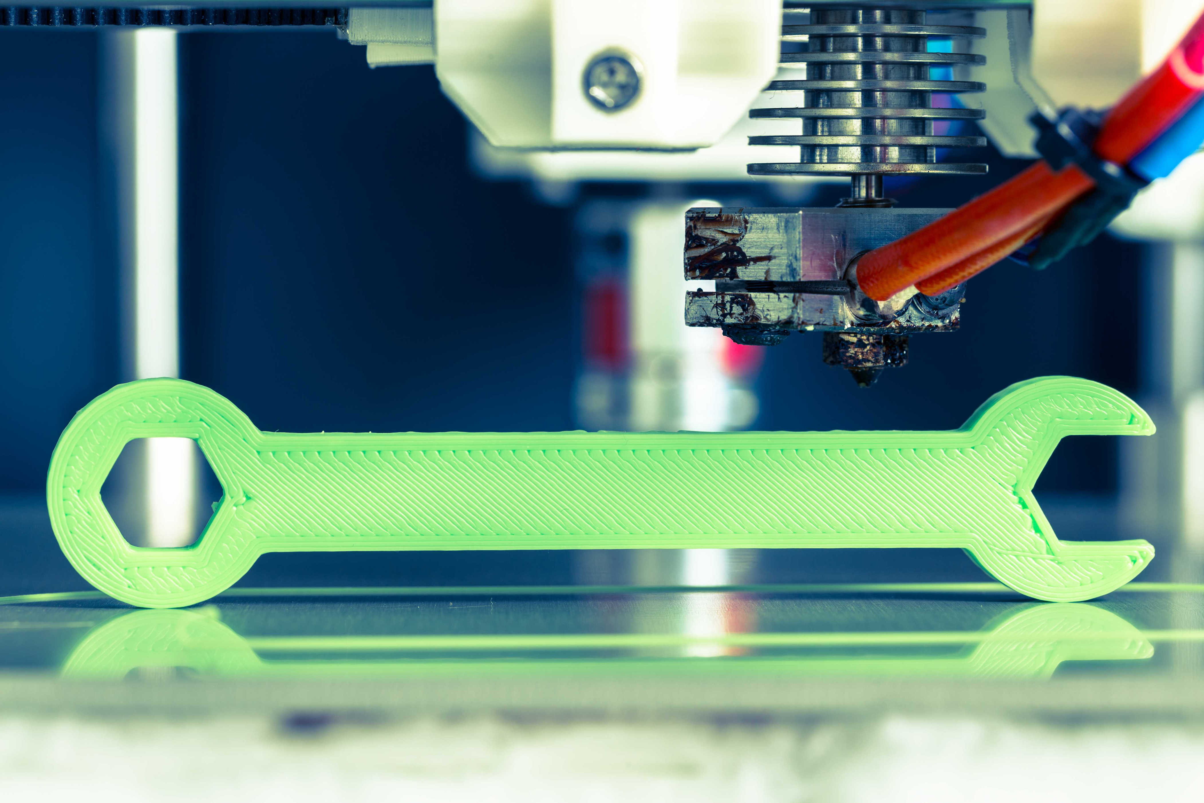 3D printer creating a plastic wrench on the print bed during printing.