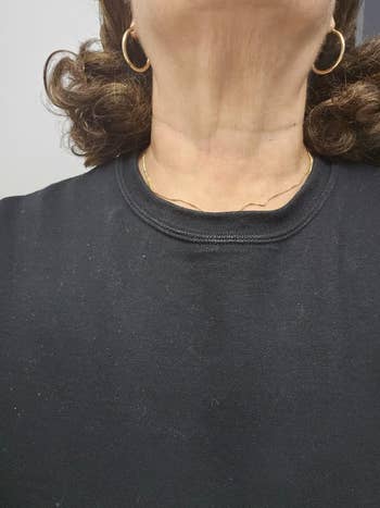 Woman wearing gold hoop earrings and a black top, featuring a subtle gold necklace, part of a shopping article