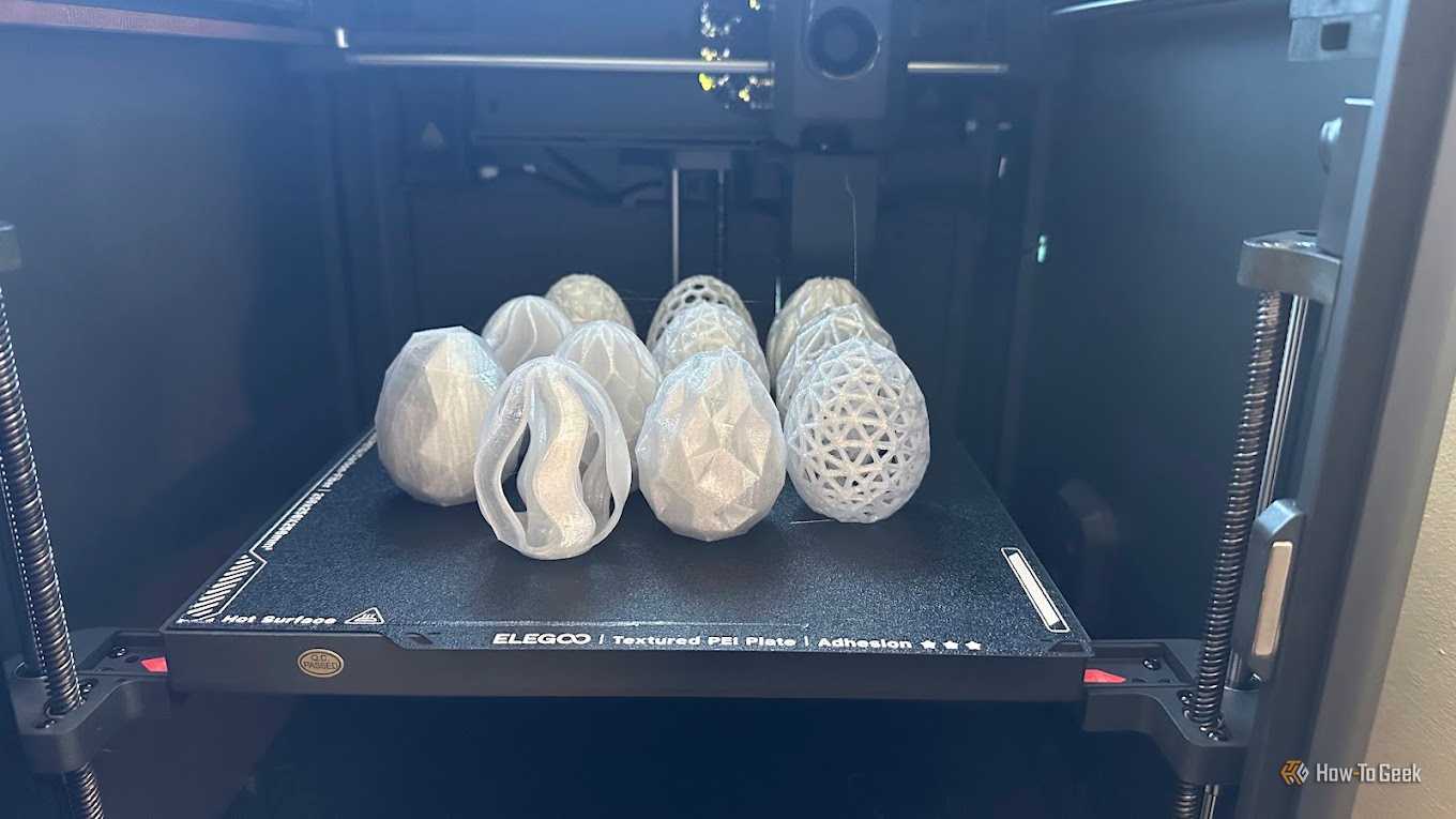 Collection of decorative 3D printed egg models on an Elegoo printer bed.